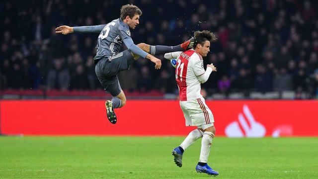 TOPSHOT - Bayern Munich's German forward Thomas Mueller (L) kicks the back of Ajax's Argentine defender Nicolas Tagliafico (R) during the UEFA Champions League Group E football match between AFC Ajax and FC Bayern Munchen at the Johan Cruyff Arena in Amsterdam on December 12, 2018.