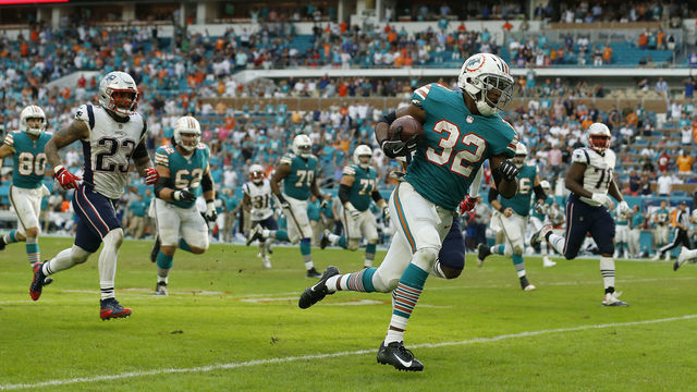 MIAMI, FL - DECEMBER 09: Kenyan Drake #32 of the Miami Dolphins runs to the endzone as time expires to score the winning touchdown as they defeat the New England Patriots 34-33 at Hard Rock Stadium on December 9, 2018 in Miami, Florida.