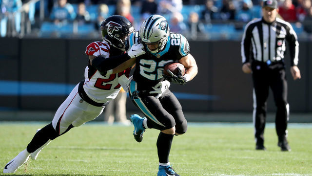 CHARLOTTE, NORTH CAROLINA - DECEMBER 23: Christian McCaffrey #22 of the Carolina Panthers runs the ball against Damontae Kazee #27 of the Atlanta Falcons in the first quarter during their game at Bank of America Stadium on December 23, 2018 in Charlotte, North Carolina.