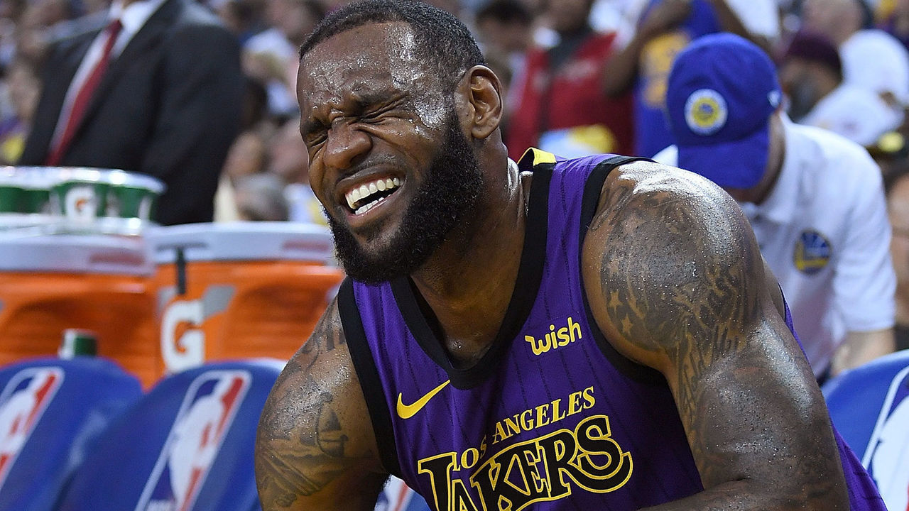 OAKLAND, CA - DECEMBER 25: LeBron James #23 of the Los Angeles Lakers crouches down in pain on the bench after he was hurt against the Golden State Warriors during the second half of their NBA Basketball game at ORACLE Arena on December 25, 2018 in Oakland, California.