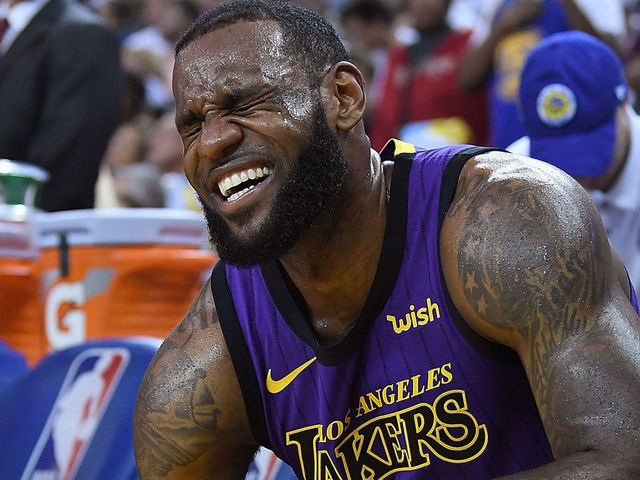 OAKLAND, CA - DECEMBER 25: LeBron James #23 of the Los Angeles Lakers crouches down in pain on the bench after he was hurt against the Golden State Warriors during the second half of their NBA Basketball game at ORACLE Arena on December 25, 2018 in Oakland, California.