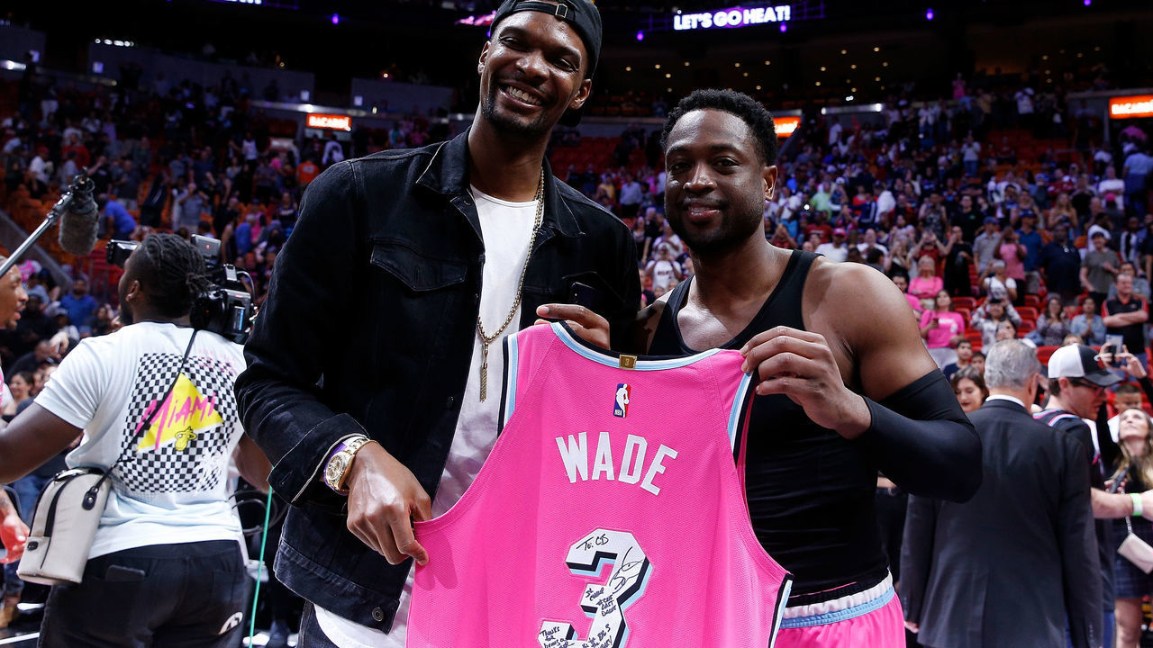 MIAMI, FL - DECEMBER 28: Dwyane Wade #3 of the Miami Heat greets former Miami Heat teammate Chris Bosh with a jersey after the game against the Cleveland Cavaliers at American Airlines Arena on December 28, 2018 in Miami, Florida.
