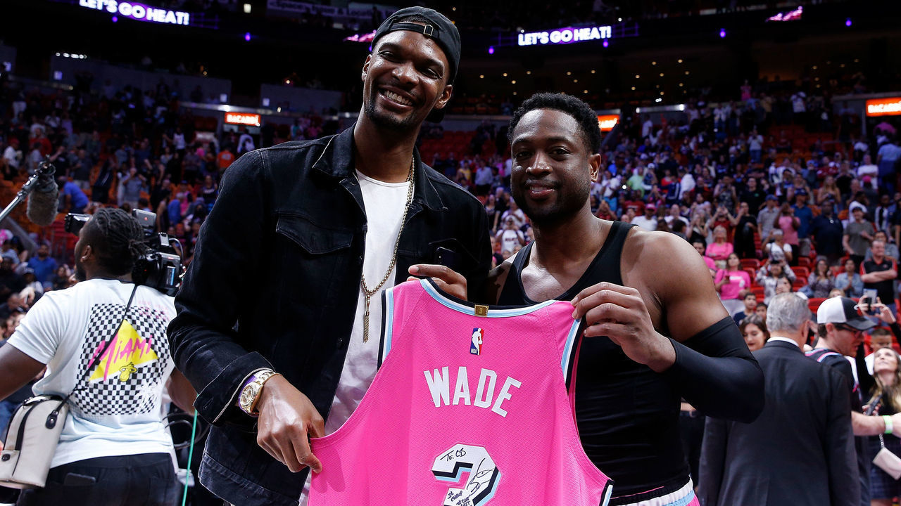 MIAMI, FL - DECEMBER 28: Dwyane Wade #3 of the Miami Heat greets former Miami Heat teammate Chris Bosh with a jersey after the game against the Cleveland Cavaliers at American Airlines Arena on December 28, 2018 in Miami, Florida.