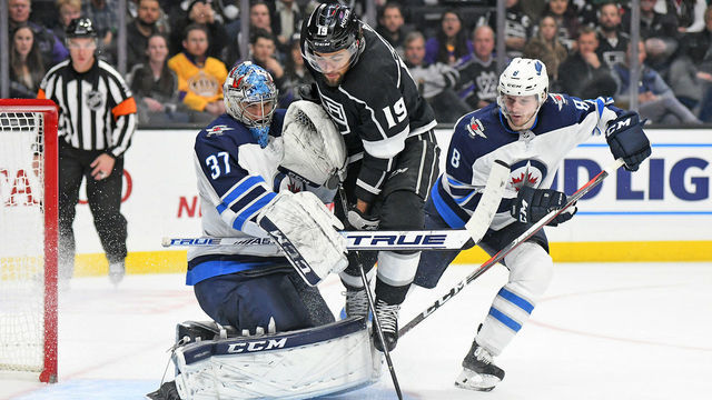 LOS ANGELES, CA - DECEMBER 18: Los Angeles Kings left wing Alex Iafallo (19) battles for a loose puck with Jacob Trouba (8) in front of Jets goaltender Connor Hellebuyck (37) during the third period of their game on December 18, 2018, at the Staples Center in Los Angeles, CA.