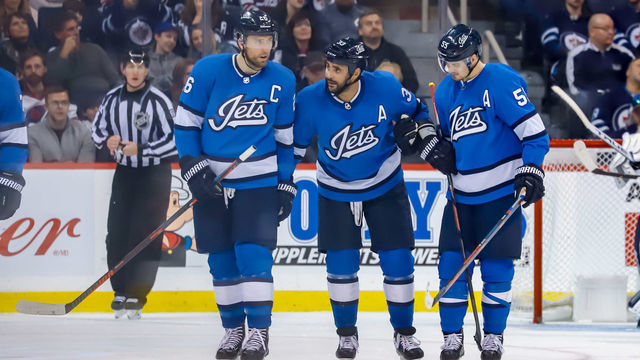 WINNIPEG, MB - DECEMBER 29: Blake Wheeler #26 and Mark Scheifele #55 of the Winnipeg Jets help teammate Dustin Byfuglien #33 off the ice during a third period stoppage in play against the Minnesota Wild at the Bell MTS Place on December 29, 2018 in Winnipeg, Manitoba, Canada.