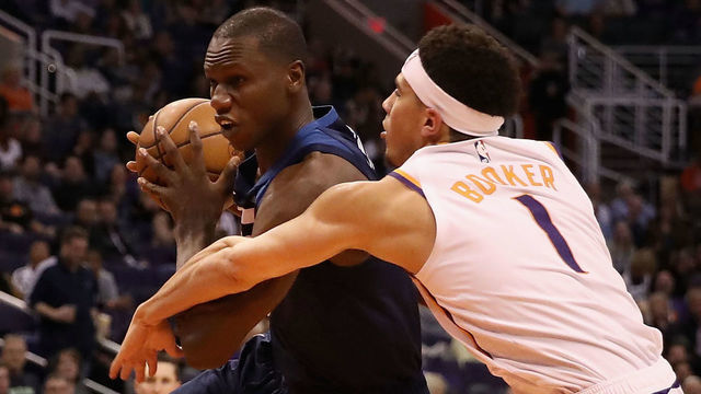 PHOENIX, ARIZONA - JANUARY 22: Gorgui Dieng #5 of the Minnesota Timberwolves controls the ball guarded by Devin Booker #1 of the Phoenix Suns during the second half of the NBA game at Talking Stick Resort Arena on January 22, 2019 in Phoenix, Arizona. The Timberwolves defeated the Suns 118-91.