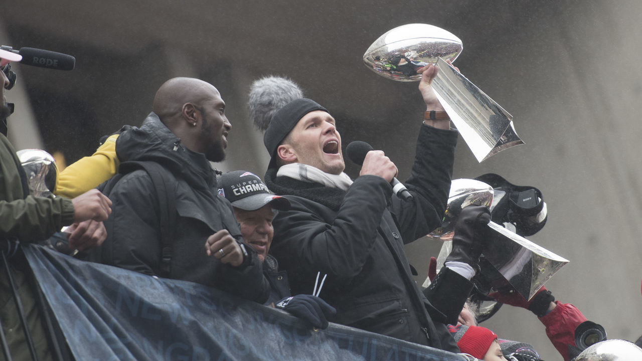 BOSTON, MA - FEBRUARY 07: New England Patriots quarterback Tom Brady (12) hoists one of the trophies to the crowd at Government Center during the Victory Parade through the streets of Boston on February 7, 2017, in Boston, Massachusetts to celebrate winning Super Bowl LI.