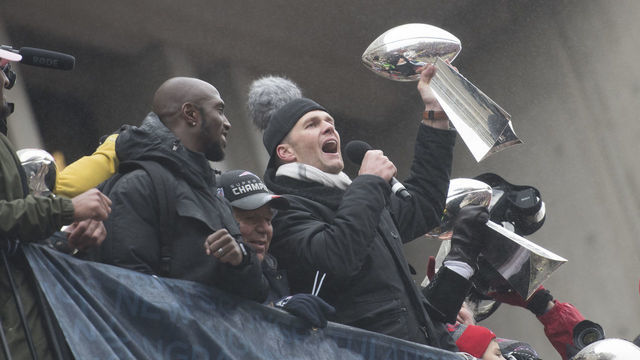 BOSTON, MA - FEBRUARY 07: New England Patriots quarterback Tom Brady (12) hoists one of the trophies to the crowd at Government Center during the Victory Parade through the streets of Boston on February 7, 2017, in Boston, Massachusetts to celebrate winning Super Bowl LI.
