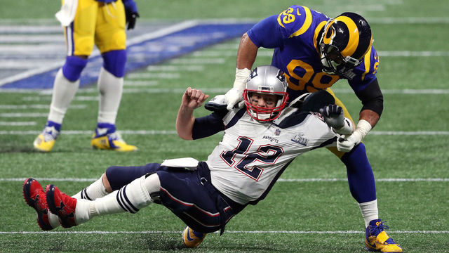 ATLANTA, GEORGIA - FEBRUARY 03: Tom Brady #12 of the New England Patriots is tackled by Aaron Donald #99 of the Los Angeles Rams in the first quarter during Super Bowl LIII at Mercedes-Benz Stadium on February 03, 2019 in Atlanta, Georgia.