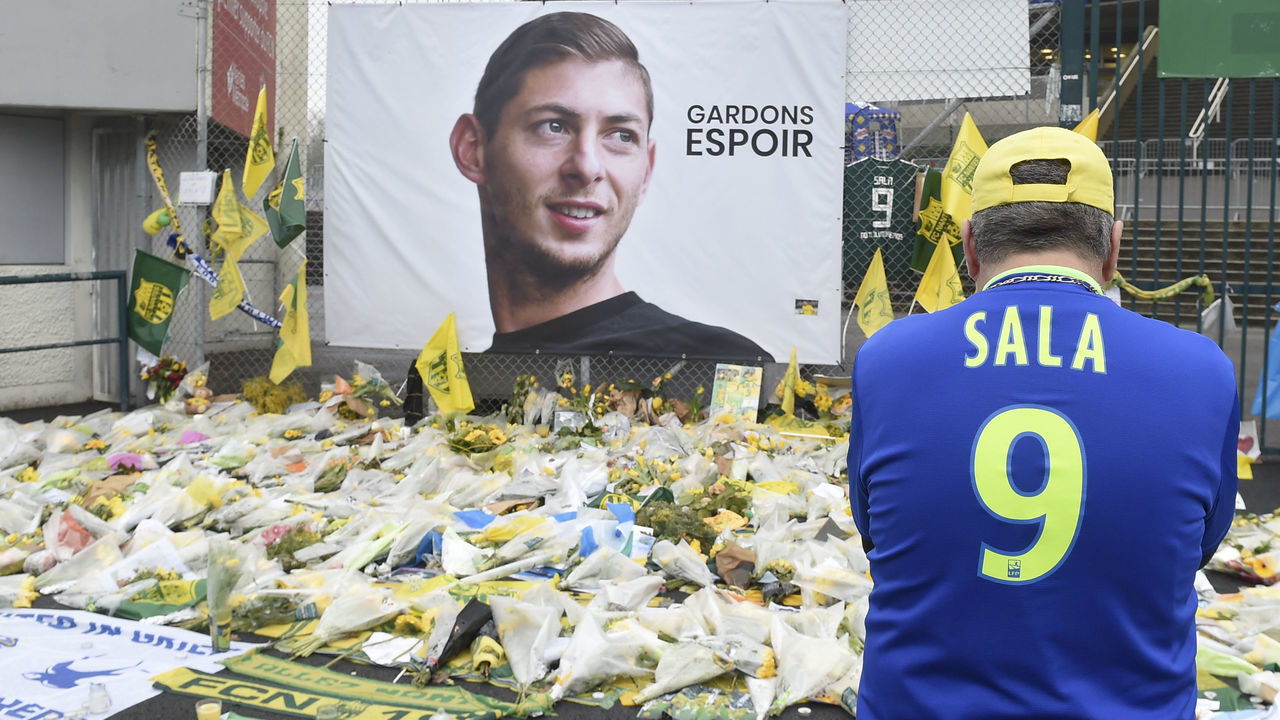 A supporter stands in front of flowers placed in front of a giant portrait of Argentinian former Nantes' forward Emilianio Sala outside La Beaujoire stadium before the French Cup football match between FC Nantes and Toulouse FC in Nantes on February 5, 2019.