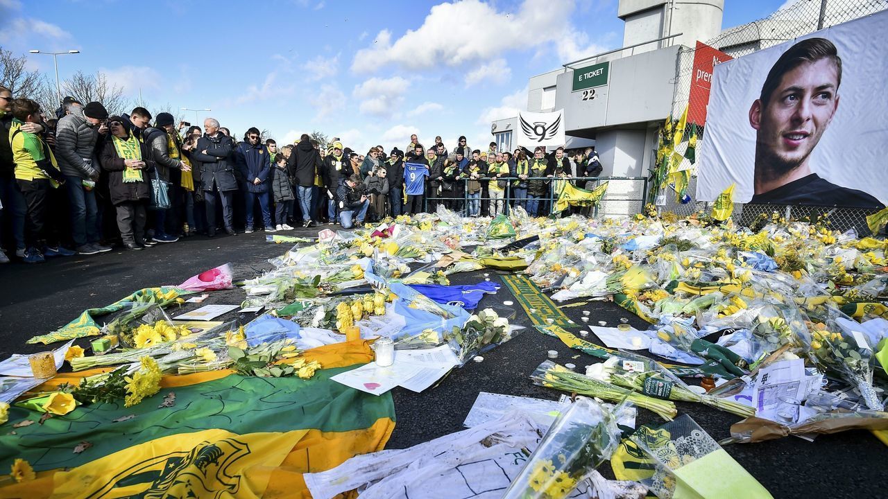 FC Nantes supporters gather in front of a portrait of late Argentinian forward Emiliano Sala to pay tribute prior to the French L1 football match between FC Nantes and Nimes Olympique at the La Beaujoire stadium in Nantes, western France on February 10, 2019. - FC Nantes football club announced on February 8, 2019 that it will freeze the #9 jersey as a tribute to Cardiff City and former Nantes footballer Emiliano Sala who died in a plane crash in the English Channel on January 21, 2019.
