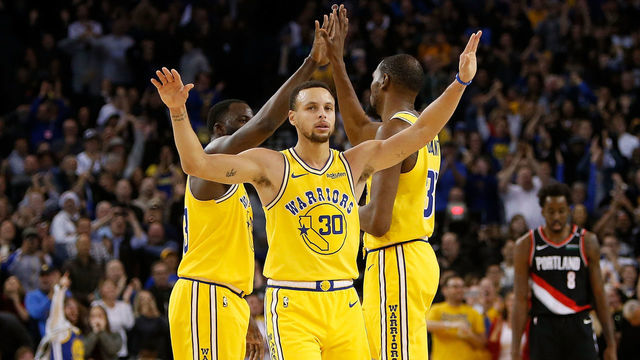 OAKLAND, CA - DECEMBER 27: Kevin Durant #35, Stephen Curry #30 and Draymond Green #23 of the Golden State Warriors celebrate after a basket against the Portland Trail Blazers at ORACLE Arena on December 27, 2018 in Oakland, California.