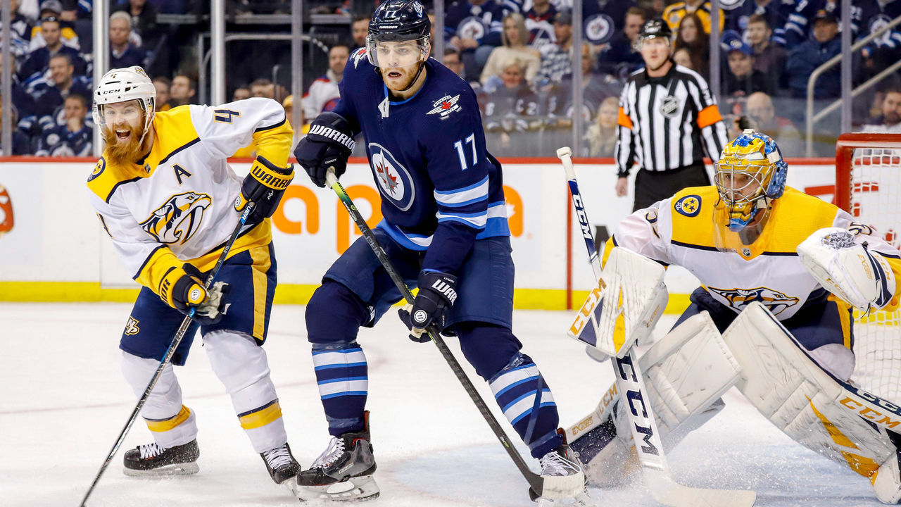 WINNIPEG, MB - MARCH 1: Adam Lowry #17 of the Winnipeg Jets stands between Ryan Ellis #4 and goaltender Pekka Rinne #35 of the Nashville Predators as they keep an eye on the play during first period action at the Bell MTS Place on March 1, 2019 in Winnipeg, Manitoba, Canada.