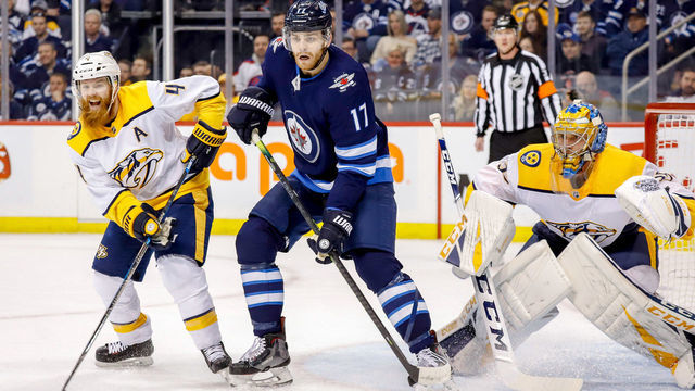 WINNIPEG, MB - MARCH 1: Adam Lowry #17 of the Winnipeg Jets stands between Ryan Ellis #4 and goaltender Pekka Rinne #35 of the Nashville Predators as they keep an eye on the play during first period action at the Bell MTS Place on March 1, 2019 in Winnipeg, Manitoba, Canada.