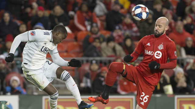 TORONTO, ON - MARCH 17: New England Revolution midfielder Luis Caicedo (27) and Toronto FC defender Laurent Ciman (26) both get airborne but Caicedo manages to head it toward midfield. Toronto FC vs New England Revolution during 2nd half action in MLS regular season play at BMO Field. This is the season opener for TFC. TFC won 3-2. Toronto Star/Rick Madonik (Rick Madonik/Toronto Star via Getty Images)