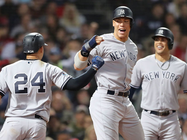 BOSTON, MA - OCTOBER 06: Gary Sanchez #24 and Aaron Judge #99 of the New York Yankees celebrate after Sanchez hit a three-run home run as teammate Giancarlo Stanton #27 watches during the seventh inning of Game Two of the American League Division Series against the Boston Red Sox at Fenway Park on October 6, 2018 in Boston, Massachusetts.