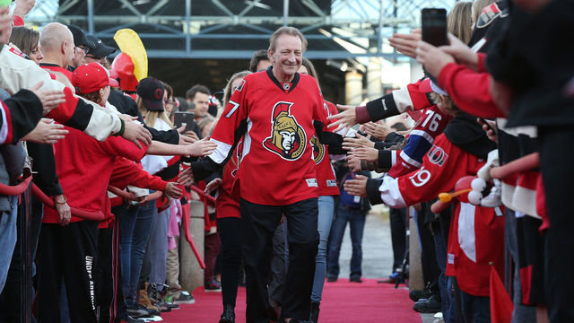 OTTAWA, ON - OCTOBER 11: Eugene Melnyk, owner of the Ottawa Senators, high-fives fans as he walks down the red carpet before the home opener against the Montreal Canadiens at Canadian Tire Centre on October 11, 2015 in Ottawa, Ontario, Canada.