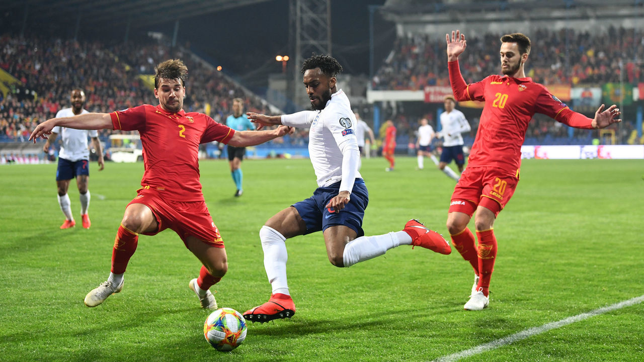 PODGORICA, MONTENEGRO - MARCH 25: Danny Rose of England takes on Filip Stojkovic (2) and Mirko Ivanic of Montenegro (20) during the 2020 UEFA European Championships Group A qualifying match between Montenegro and England at Podgorica City Stadium on March 25, 2019 in Podgorica, Montenegro.