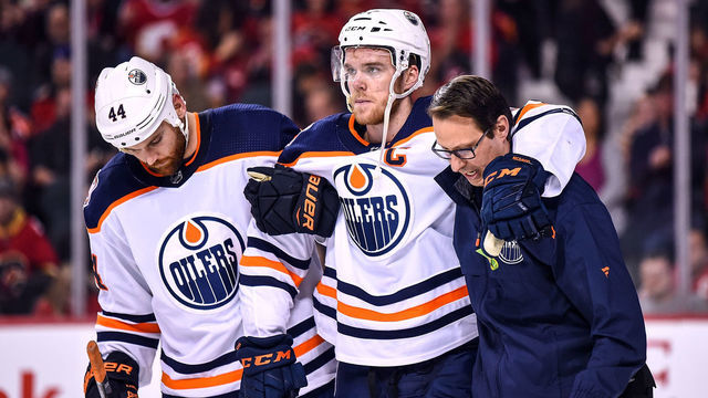 CALGARY, AB - APRIL 06: Edmonton Oilers Center Connor McDavid (97) is helped off the ice by Edmonton Oilers Right Wing Zack Kassian (44) and a trainer after crashing into Calgary Flames net during the second period of an NHL game where the Calgary Flames hosted the Edmonton Oilers on April 6, 2019, at the Scotiabank Saddledome in Calgary, AB.
