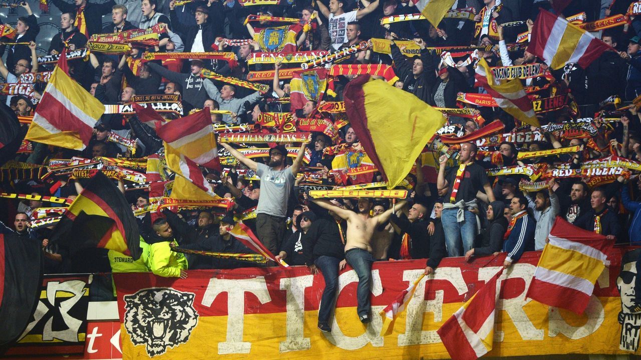 Lens' supporters wave flags and hold scarves of their team during the French L1 football match between Lille (LOSC) and RC Lens on May 3, 2015, at the Pierre Mauroy Stadium in Villeneuve-d'Ascq, northern France. AFP PHOTO / DENIS CHARLET