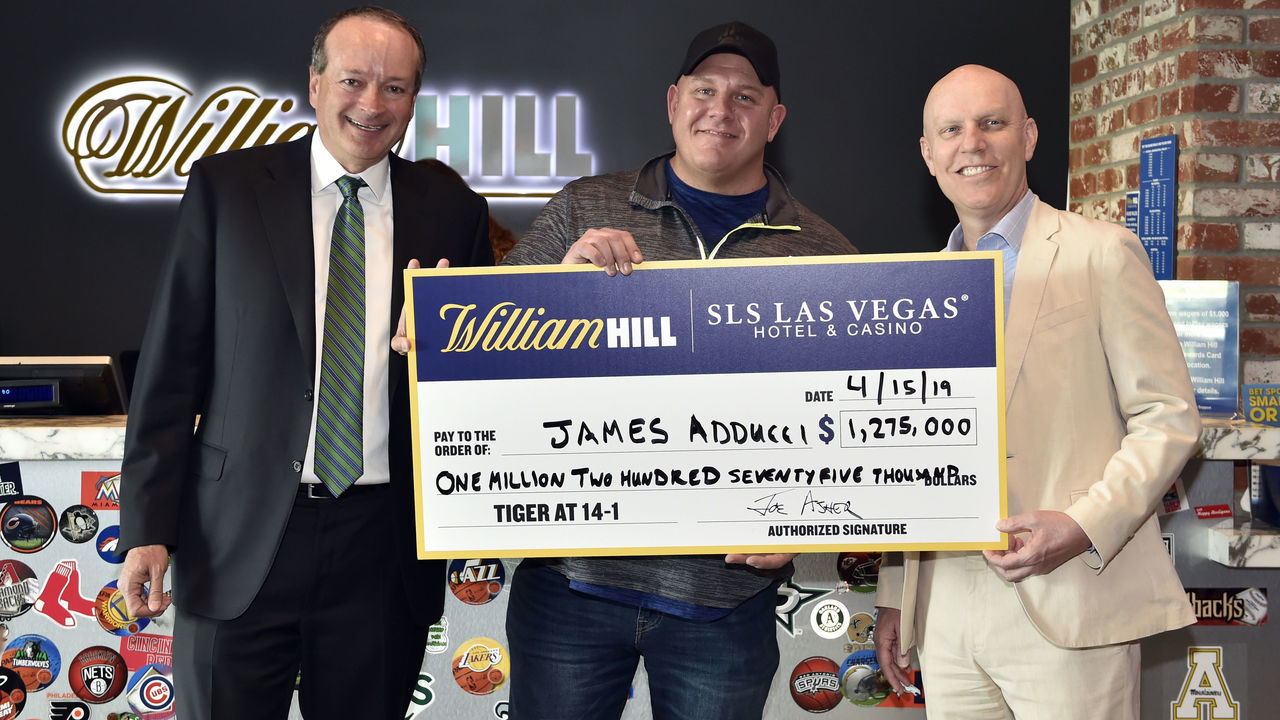 LAS VEGAS, NEVADA - APRIL 15: (L-R) William Hill US CEO Joe Asher, James Adducci and SLS Las Vegas general manager Paul Hobson stand with an ceremonial check of Adducci's winnings after cashing his winning ticket at the William Hill Sports Book at SLS Las Vegas Hotel on April 15, 2019 in Las Vegas, Nevada. Adducci placed an USD 85,000 wager on golfer Tiger Woods to win the 2019 Masters Tournament.