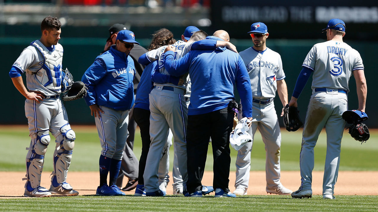 OAKLAND, CA - APRIL 20: Starting pitcher Matt Shoemaker #34 of the Toronto Blue Jays is assisted from the field after a collision while getting the out of Matt Chapman #26 of the Oakland Athletics in the bottom of the third inning at Oakland-Alameda County Coliseum on April 20, 2019 in Oakland, California.