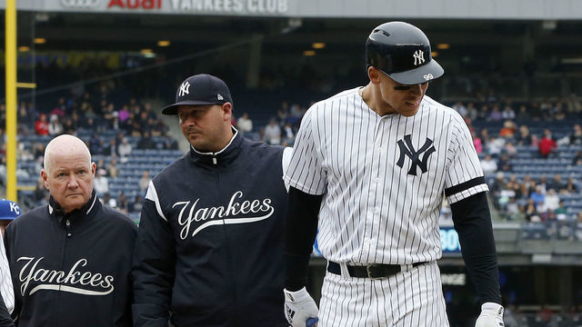 NEW YORK, NEW YORK - APRIL 20: Aaron Judge #99 of the New York Yankees is checked on by bench coach Josh Bard, trainer Steve Donohue and first base coach Reggie Willits #50 prior to leaving a game against the Kansas City Royals in the sixth inning at Yankee Stadium on April 20, 2019 in New York City.