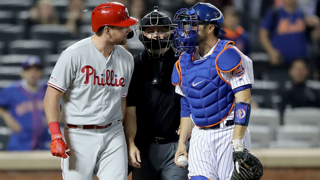 NEW YORK, NEW YORK - APRIL 23: Rhys Hoskins #17 of the Philadelphia Phillies and Travis d'Arnaud #18 of the New York Mets have words as they are separated by home plate umpire Scott Barry in the ninth inning at Citi Field on April 23, 2019 in the Flushing neighborhood of the Queens borough of New York City.The New York Mets defeated the Philadelphia Phillies 9-0.
