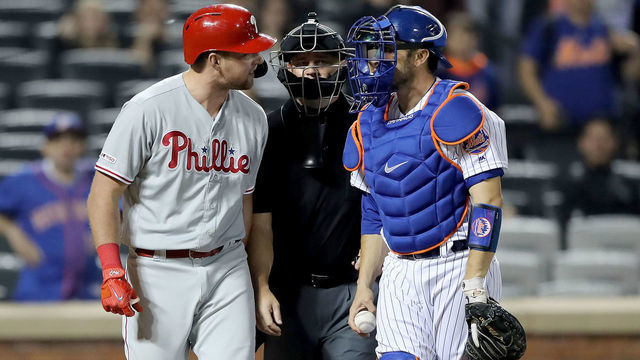 NEW YORK, NEW YORK - APRIL 23: Rhys Hoskins #17 of the Philadelphia Phillies and Travis d'Arnaud #18 of the New York Mets have words as they are separated by home plate umpire Scott Barry in the ninth inning at Citi Field on April 23, 2019 in the Flushing neighborhood of the Queens borough of New York City.The New York Mets defeated the Philadelphia Phillies 9-0.