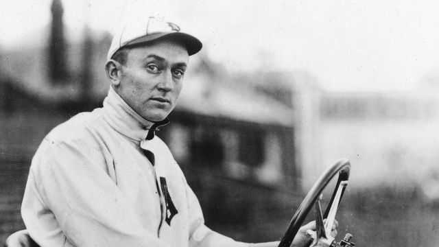 American baseball player Ty Cobb (1886 - 1961) sits behind the wheel of a car, wearing his Detroit Tigers uniform, 1900s.