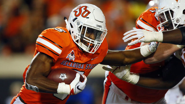 STILLWATER, OK - OCTOBER 27: Running back Justice Hill #5 of the Oklahoma State Cowboys tries to stiff arm defensive lineman Chris Nelson #97 of the Texas Longhorns who facemasks him in return during the second quarter on October 27, 2018 at Boone Pickens Stadium in Stillwater, Oklahoma. Oklahoma State won 38-35.