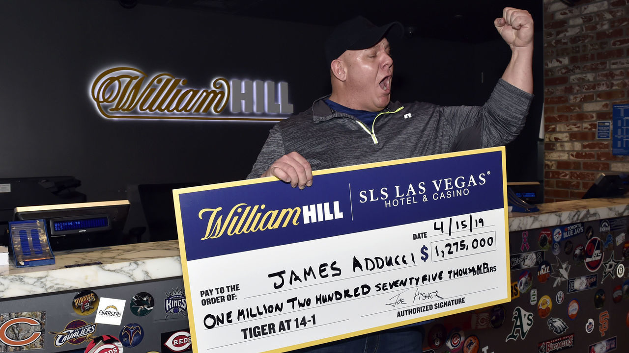 LAS VEGAS, NEVADA - APRIL 15: James Adducci of Wisconsin reacts with an ceremonial check of his winnings after cashing his ticket at the William Hill Sports Book at SLS Las Vegas Hotel on April 15, 2019 in Las Vegas, Nevada. Adducci placed an USD 85,000 wager on golfer Tiger Woods to win the 2019 Masters Tournament.