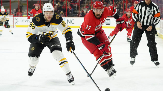 RALEIGH, NC - OCTOBER 30: Carolina Hurricanes Defenceman Justin Faulk (27) and Boston Bruins Right Wing David Pastrnak (88) chase down a loose puck during a game between the Boston Bruins and the Carolina Hurricanes at the PNC Arena in Raleigh, NC on October 30, 2018.
