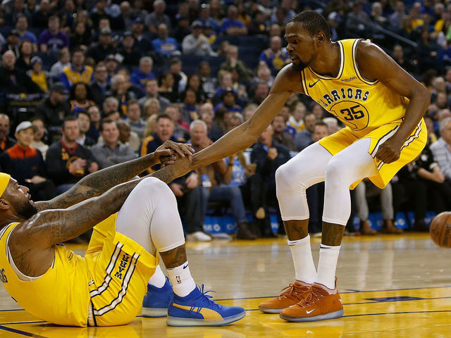 OAKLAND, CA - FEBRUARY 21: DeMarcus Cousins #0 of the Golden State Warriors is helped to his feet by teammate Kevin Durant #35 after drawing an offensive foul against the Sacramento Kings at ORACLE Arena on February 21, 2019 in Oakland, California.