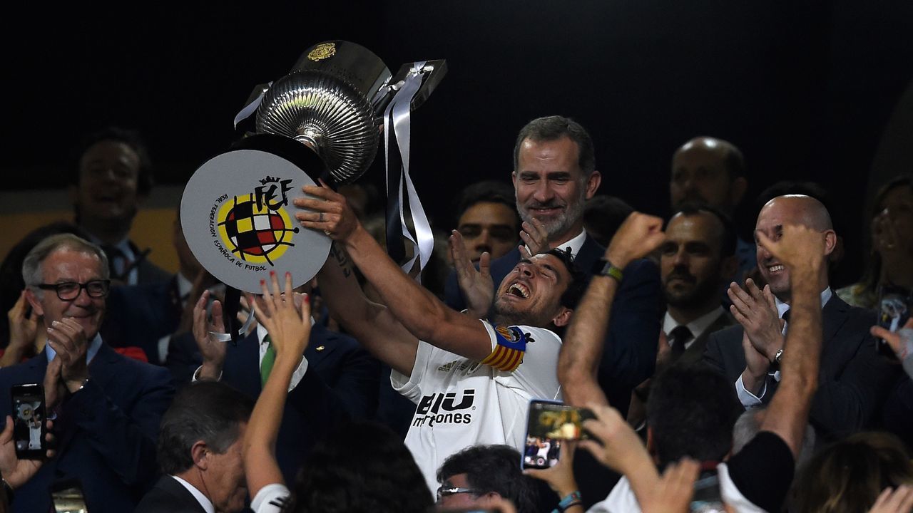 Valencia's Spanish midfielder Daniel Parejo holds the trophy in front of Spain´s King Felipe VI as he celebrates after winning the 2019 Spanish Copa del Rey (King's Cup) final football match against Barcelona at the Benito Villamarin stadium in Sevilla on May 25, 2019.