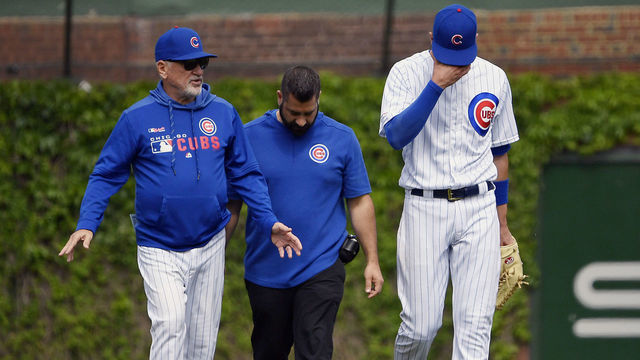 CHICAGO, ILLINOIS - MAY 26: Kris Bryant #17 of the Chicago Cubs reacts while leaving the game with Joe Maddon #70 of the Chicago Cubs and medical staff after colliding trying to catch a ball in the sixth inning against the Cincinnati Reds at Wrigley Field on May 26, 2019 in Chicago, Illinois.