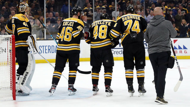 BOSTON, MASSACHUSETTS - MAY 29: Matt Grzelcyk #48 of the Boston Bruins is taken off the ice by David Krejci #46 and Jake DeBrusk #74 after being hit into the boards by Oskar Sundqvist (not pictured) #70 of the St. Louis Blues during the first period in Game Two of the 2019 NHL Stanley Cup Final at TD Garden on May 29, 2019 in Boston, Massachusetts.