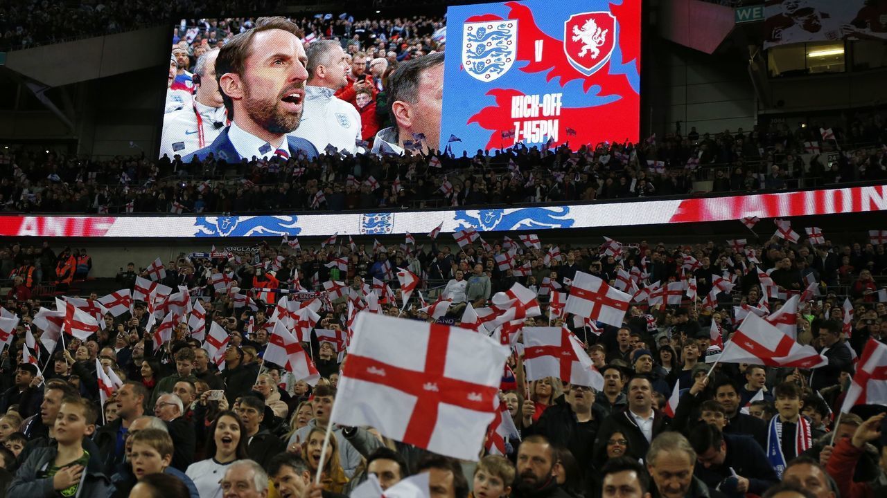 England's manager Gareth Southgate is shown on the screen as supporters wave flags during the playing of the national anthem ahead of the UEFA Euro 2020 Group A qualification football match between England and Czech Replublic at Wembley Stadium in London on March 22, 2019.