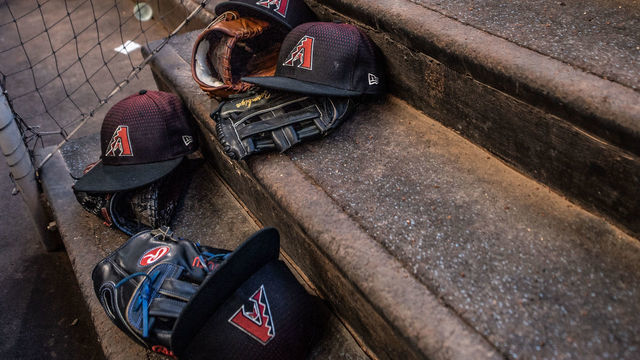 MIAMI, FL - JUNE 25: A detailed view of the New Era caps and and Rawlings gloves for the Arizona Diamondbacks in the dugout before the game against the Miami Marlins at Marlins Park on June 25, 2018 in Miami, Florida.