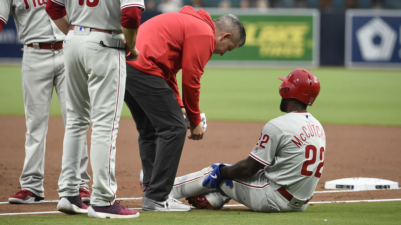 SAN DIEGO, CA - JUNE 3: A trainer looks at Andrew McCutchen #22 of the Philadelphia Phillies after he was tagged out during the first inning of a baseball game against the San Diego Padres at Petco Park June 3, 2019 in San Diego, California.