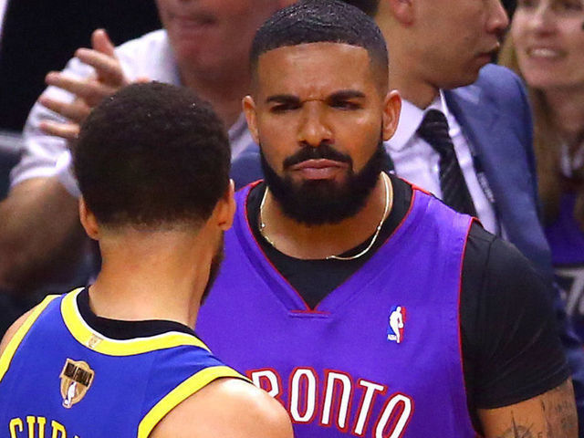 TORONTO, ONTARIO - MAY 30: Rapper Drake and Stephen Curry #30 of the Golden State Warriors exchange words during a timeout in the first quarter during Game One of the 2019 NBA Finals between the Golden State Warriors and the Toronto Raptors at Scotiabank Arena on May 30, 2019 in Toronto, Canada.