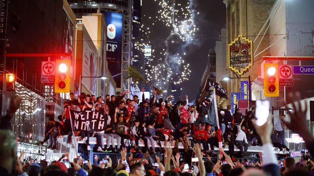 TORONTO, ON - JUNE 13: Toronto Raptors fans celebrate atop a bus after the team beat the Golden State Warriors in Game Six of the NBA Finals, on June 13, 2019 in Toronto, Canada.