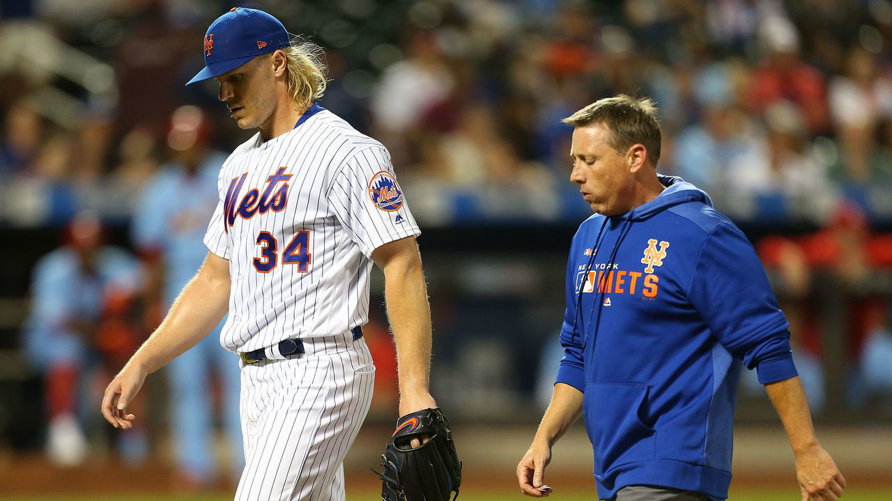 NEW YORK, NEW YORK - JUNE 15: Noah Syndergaard #34 of the New York Mets walks off the field with head trainer Brian Chicklo in the seventh inning during the game against the St. Louis Cardinals at Citi Field on June 15, 2019 in New York City.