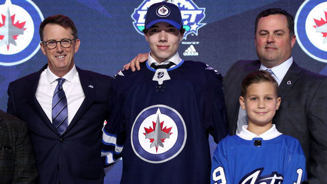 VANCOUVER, BRITISH COLUMBIA - JUNE 21: (L-R) Executive Chairman Mark Chipman, Ville Heinola, 20th overall pick of the Winnipeg Jets, and director of amateur scouting Mark Hillier pose for a group photo during the first round of the 2019 NHL Draft at Rogers Arena on June 21, 2019 in Vancouver, Canada.