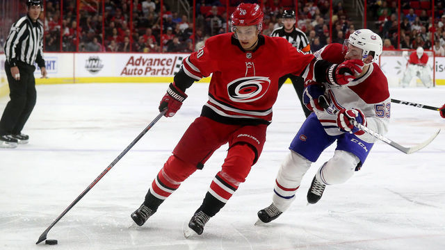 RALEIGH, NC - MARCH 24: Sebastian Aho #20 of the Carolina Hurricanes controls the puck away from Victor Mete #53 of the Montreal Canadiens during an NHL game on March 24, 2019 at PNC Arena in Raleigh, North Carolina.