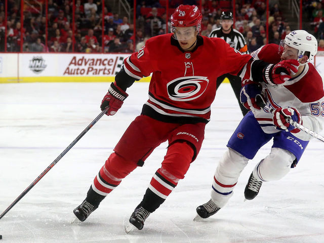 RALEIGH, NC - MARCH 24: Sebastian Aho #20 of the Carolina Hurricanes controls the puck away from Victor Mete #53 of the Montreal Canadiens during an NHL game on March 24, 2019 at PNC Arena in Raleigh, North Carolina.