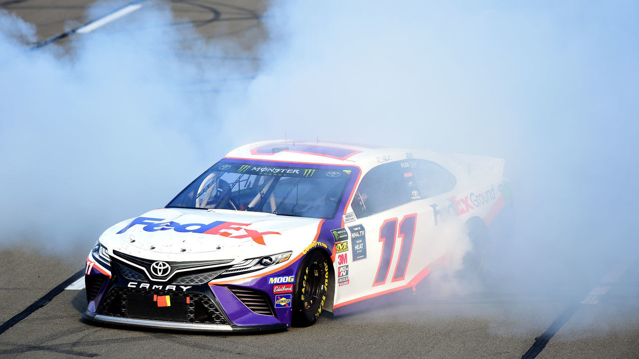 LONG POND, PENNSYLVANIA - JULY 28: Denny Hamlin, driver of the #11 FedEx Ground Toyota, celebrates with a burnout after winning the Monster Energy NASCAR Cup Series Gander RV 400 at Pocono Raceway on July 28, 2019 in Long Pond, Pennsylvania.