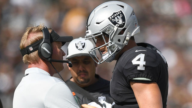 OAKLAND, CA - SEPTEMBER 30: Head coach Jon Gruden of the Oakland Raiders talks with his quarterback Derek Carr #4 on the sidelines against the Cleveland Browns during the first quarter of their NFL football game at Oakland-Alameda County Coliseum on September 30, 2018 in Oakland, California.