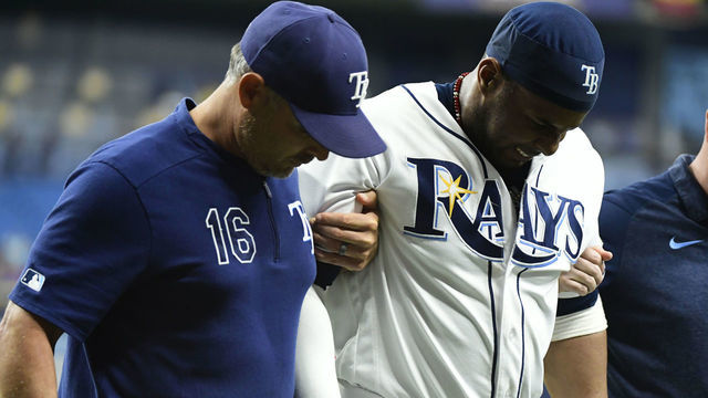 ST. PETERSBURG, FLORIDA - JULY 22: Yandy Diaz #2 of the Tampa Bay Rays gets helped off the field by manager Kevin Cash #16 after injuring his left foot during the ninth inning of a baseball game against the Boston Red Sox at Tropicana Field on July 22, 2019 in St. Petersburg, Florida.