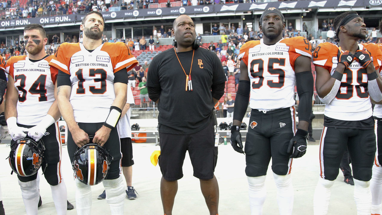 TORONTO, ON - JULY 06: Head coach DeVone Claybrooks (center) with David Mackie #34 and Mike Reilly #13 and Darius Allen #95 and Shaq Johnson #88 of the BC Lions during the anthem before a game against the Toronto Argonauts at BMO Field on July 6, 2019 in Toronto, Canada. BC defeated Toronto 18-17.